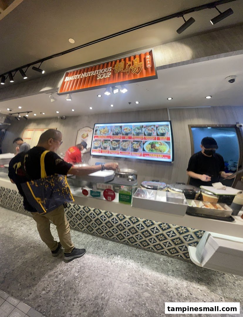 A customer orders at the Beauty Nutritious Soup stall, featuring a digital menu board and counter.