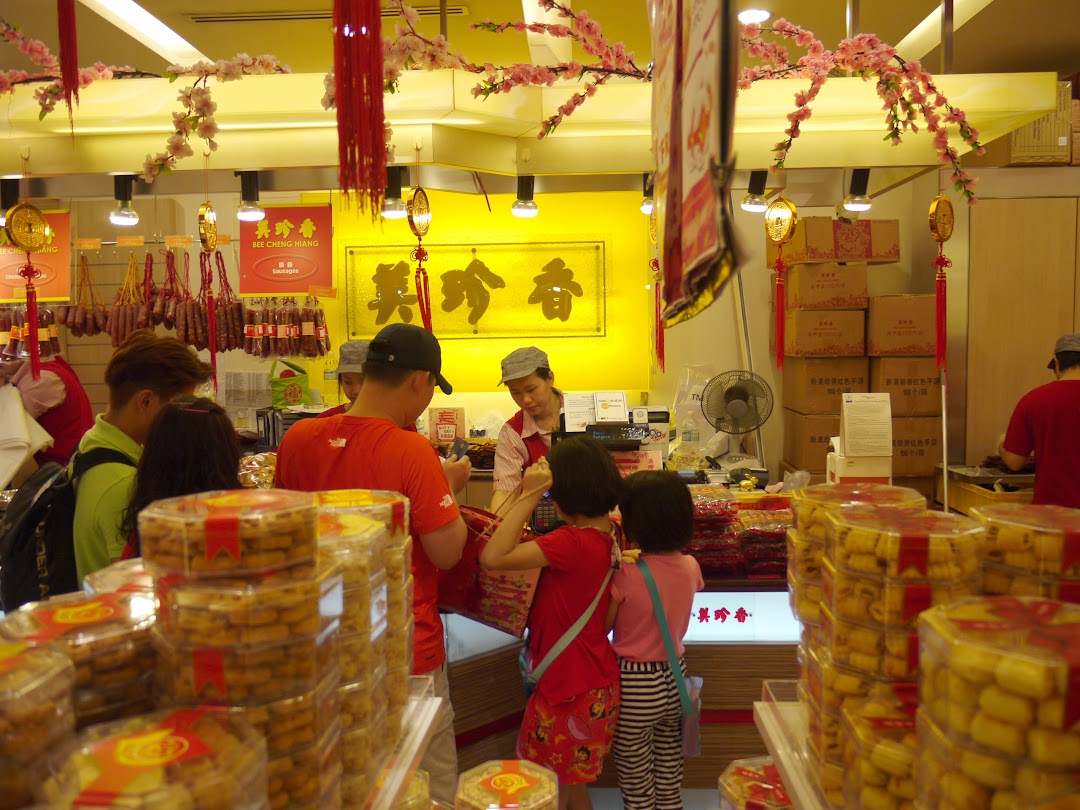 Customers and staff in a bustling Bee Cheng Hiang store, featuring traditional decorations and various products.