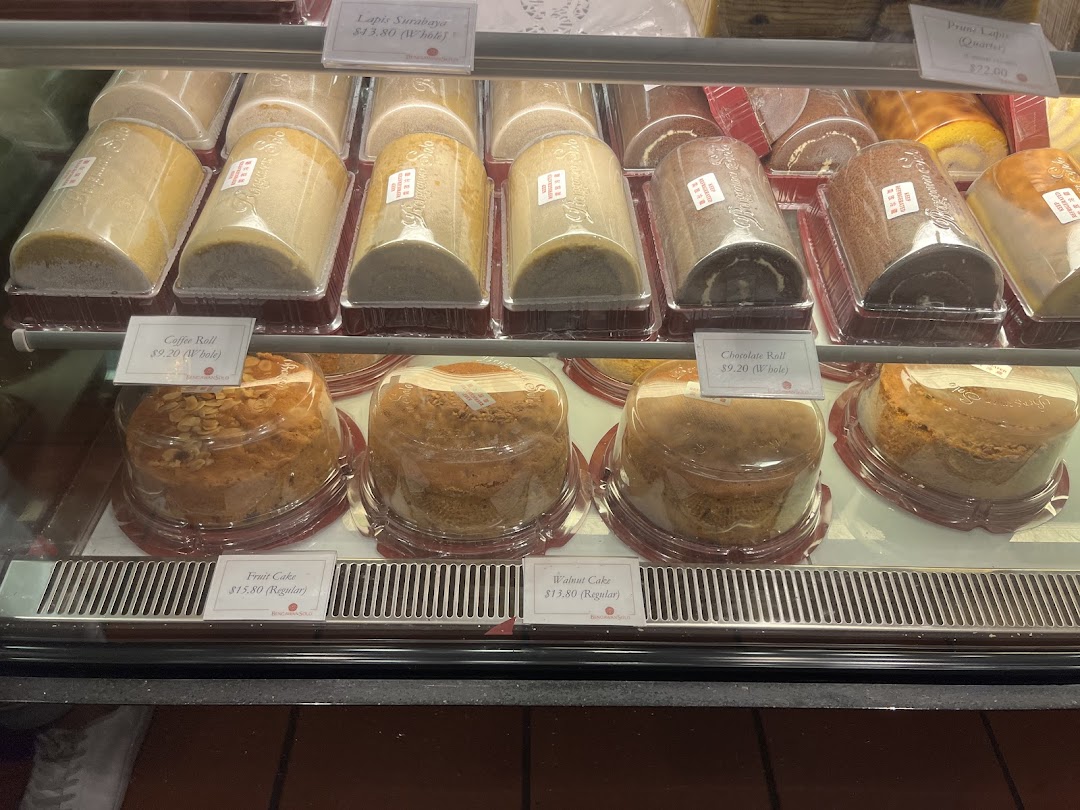A display case filled with various cakes and rolls, including Lapis Surabaya and Fruit Cake, at Bengawan Solo.