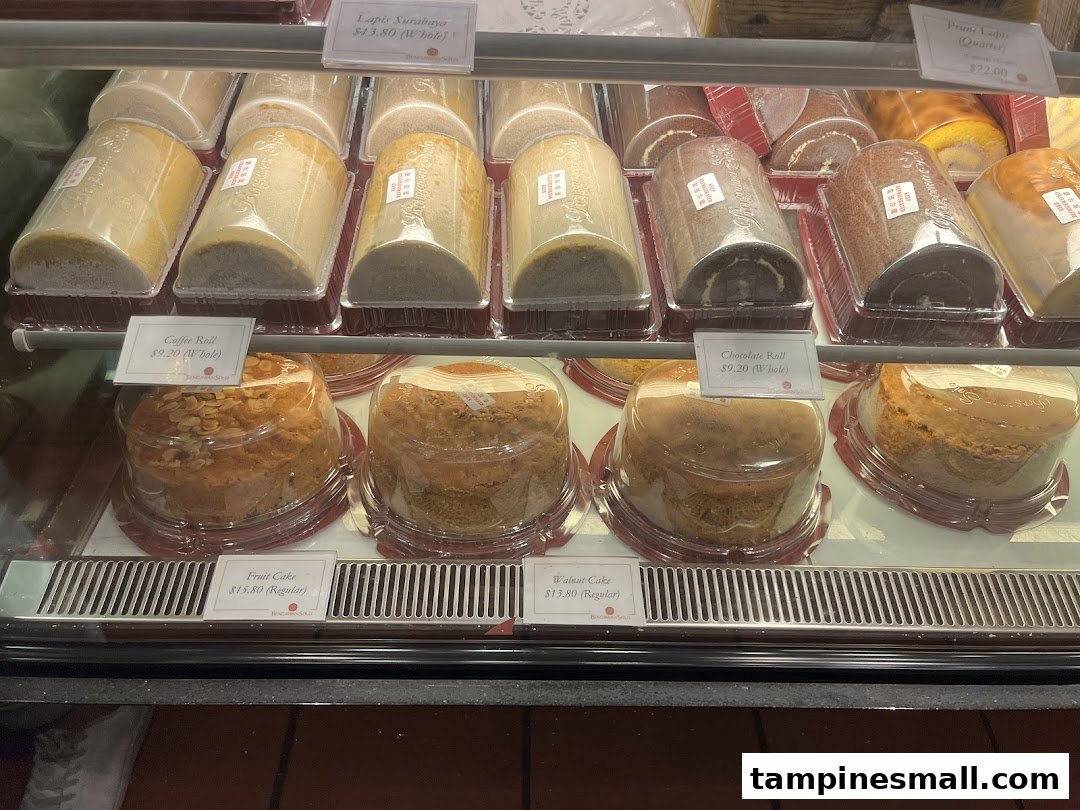 A display case filled with various cakes and rolls, including Lapis Surabaya and Fruit Cake, at Bengawan Solo.