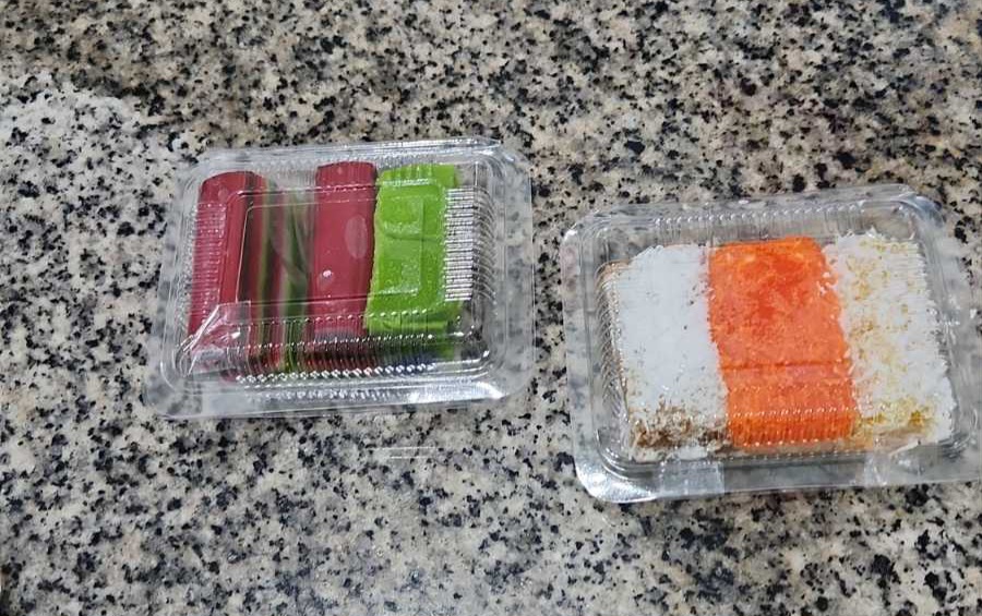 Two plastic containers of colorful traditional Indonesian cakes on a speckled countertop.