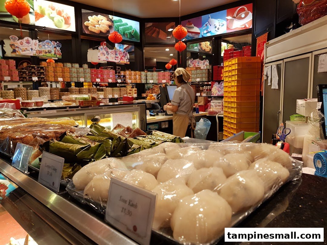 Interior view of Bengawan Solo showcasing a wide array of traditional Indonesian snacks and pastries, with a staff member at the counter.