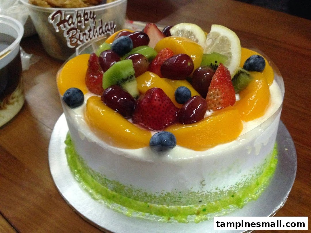 A vibrant fruit cake topped with fresh berries, peaches, kiwi, and grapes, ready for celebration.