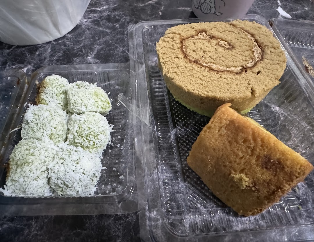 An assortment of traditional Indonesian cakes and desserts, including a roll cake and coconut-covered treats.