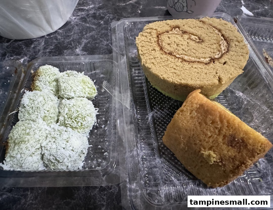An assortment of traditional Indonesian cakes and desserts, including a roll cake and coconut-covered treats.