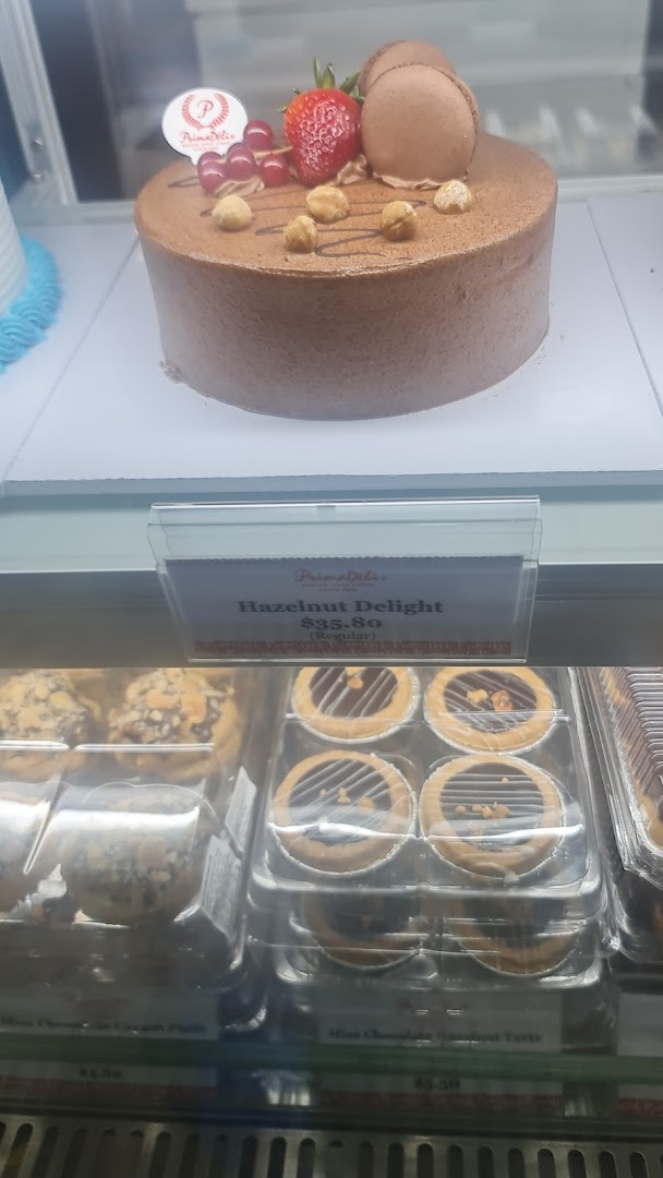 A delicious chocolate cake with berries and nuts, alongside mini tarts, displayed in a bakery case.