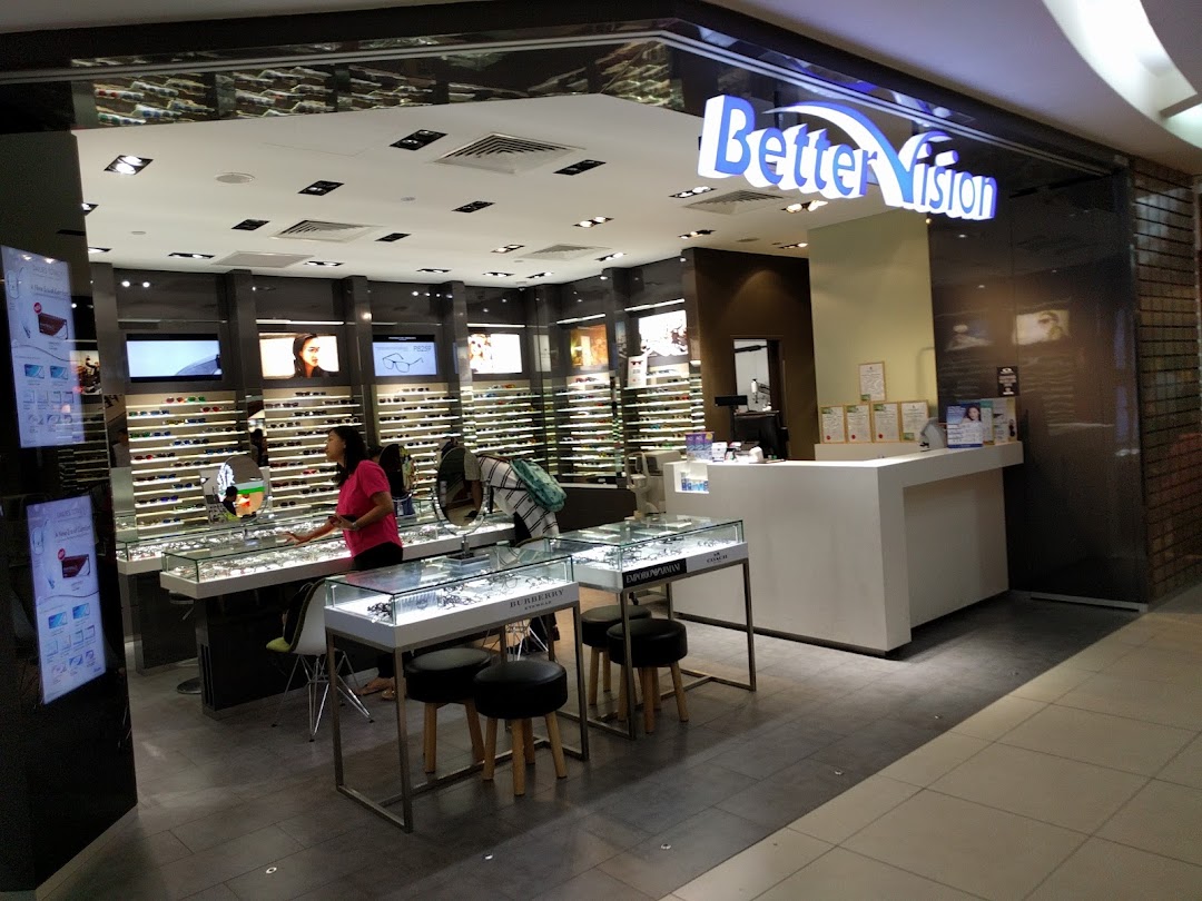 Interior view of Better Vision eyewear shop featuring display cases, a staff member, and reception counter.