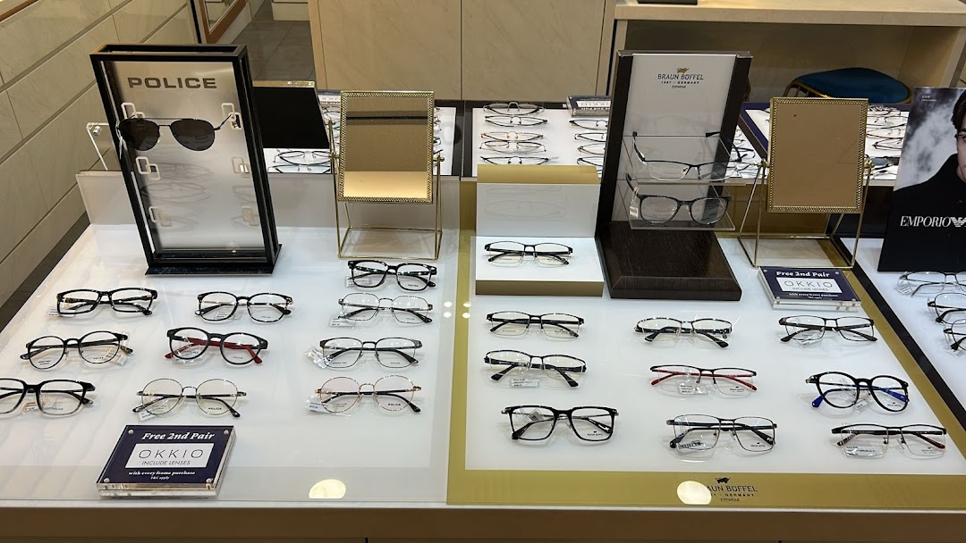 A bright display table showcasing a wide selection of eyeglasses and sunglasses from various brands.