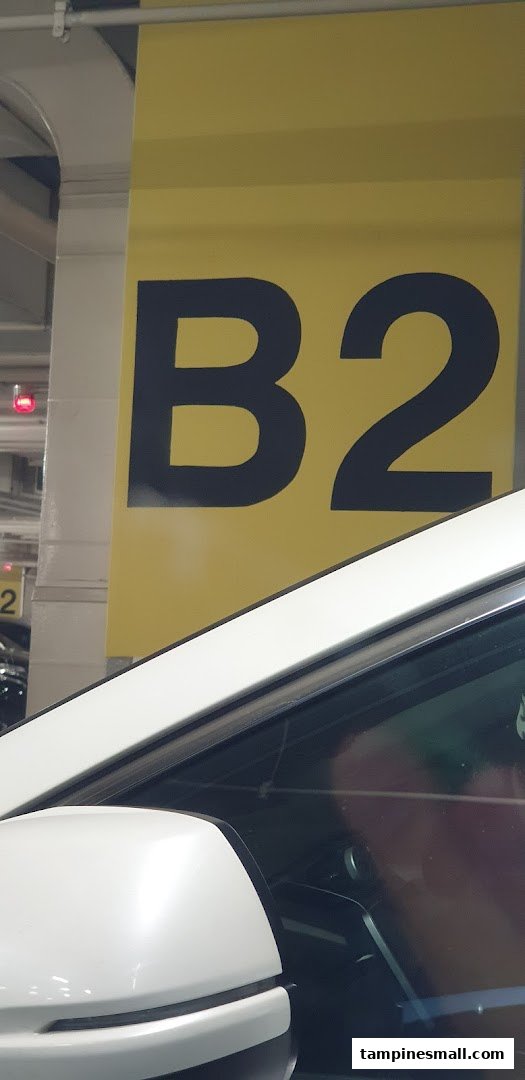 A large yellow sign indicating 'B2' in a parking deck, with a white car visible.