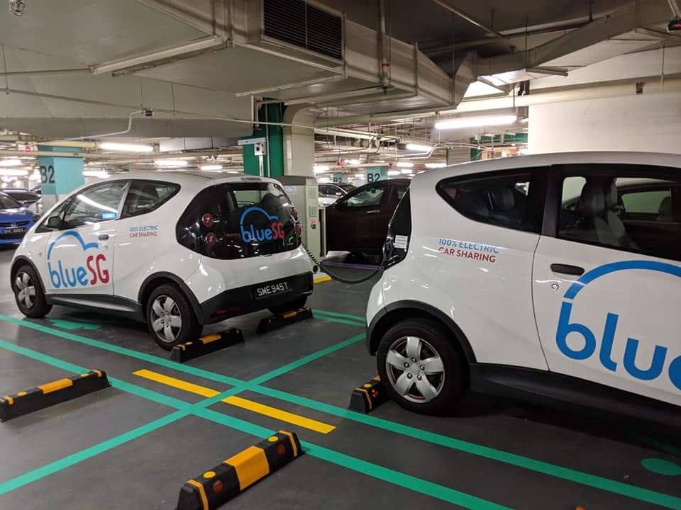 Two BlueSG electric car-sharing vehicles are parked and charging in a mall's underground car park.