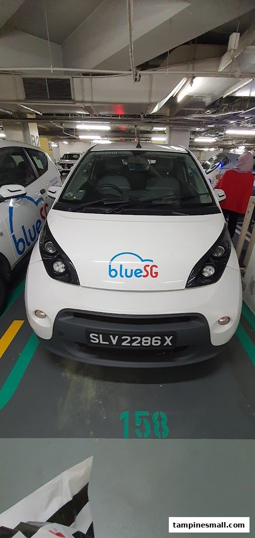 A white BlueSG electric car parked in an underground parking lot at Tampines Mall.