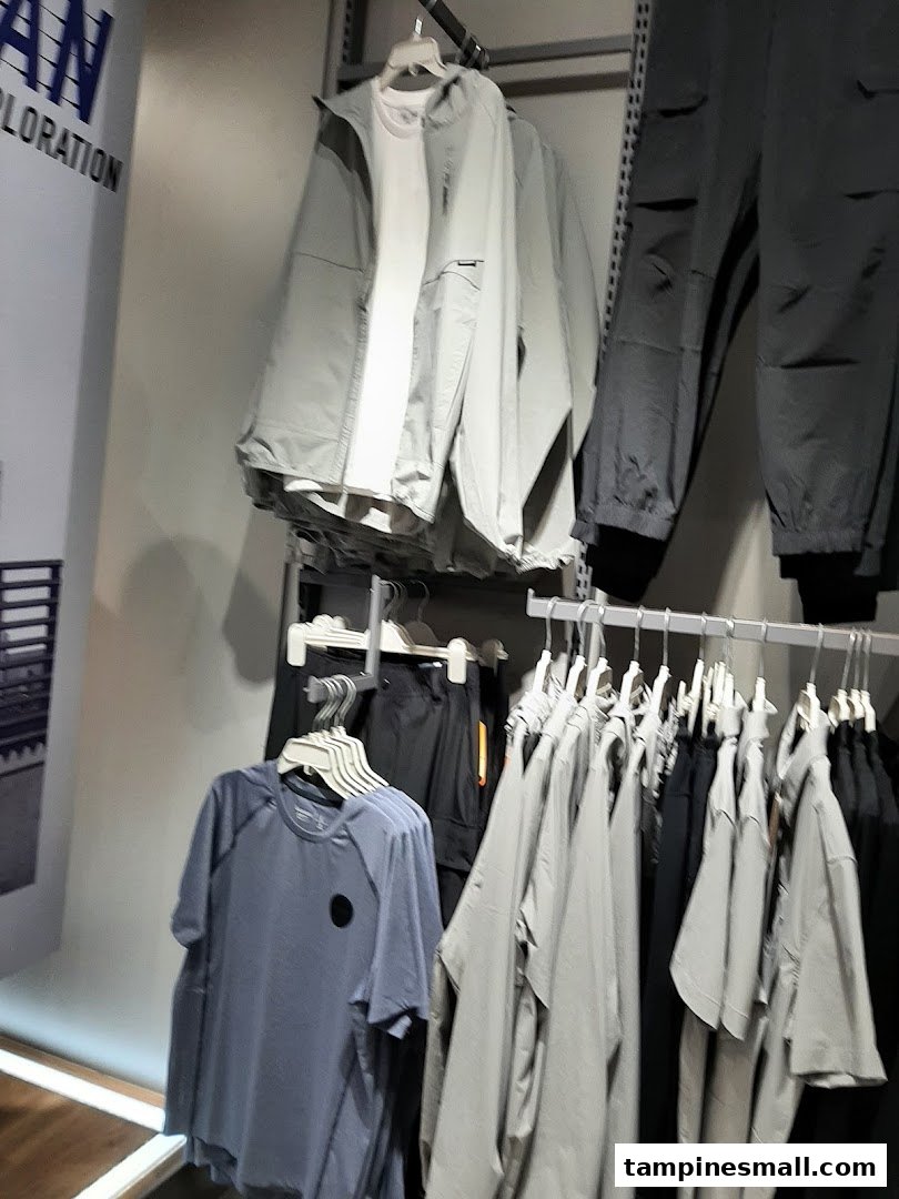Clothing racks displaying various casual wear, including jackets, t-shirts, and pants, inside a retail store.