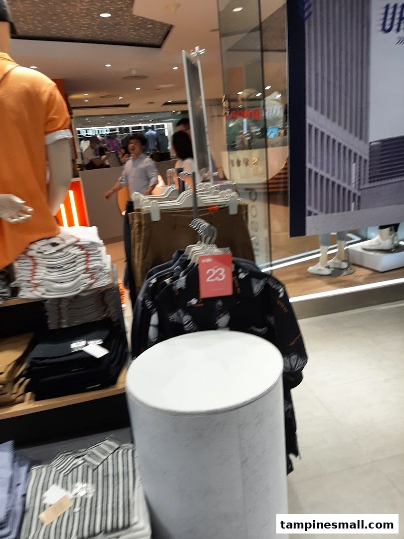 Interior view of Bossini, showcasing casual wear on mannequins and racks, with customers browsing.
