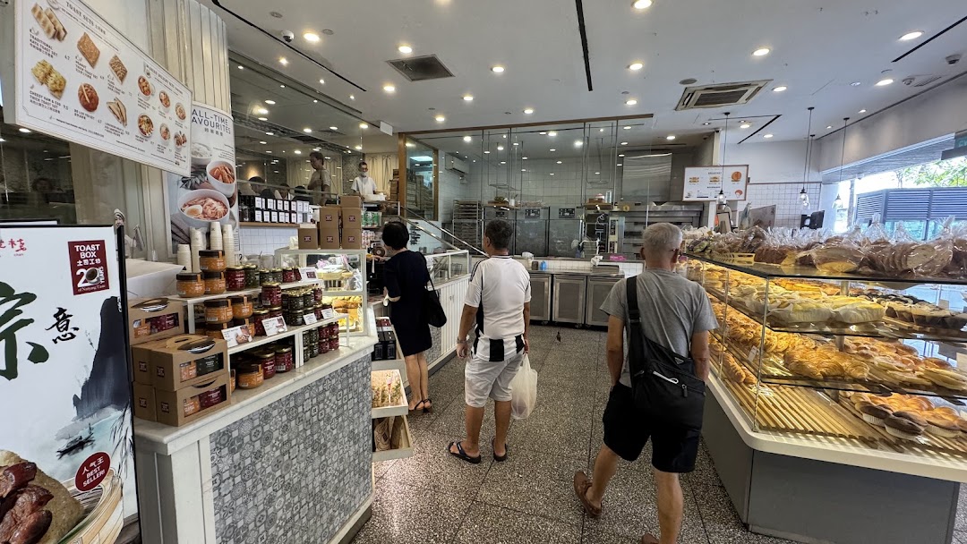 Customers browse a brightly lit BreadTalk bakery, featuring display cases filled with various baked goods and packaged items.