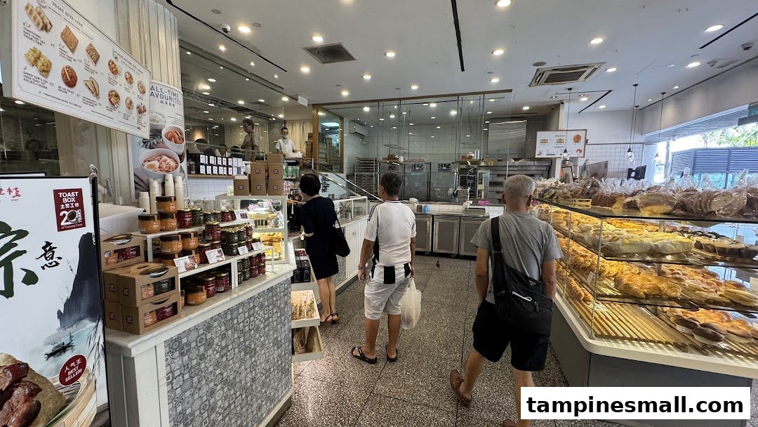 Customers browse a brightly lit BreadTalk bakery, featuring display cases filled with various baked goods and packaged items.