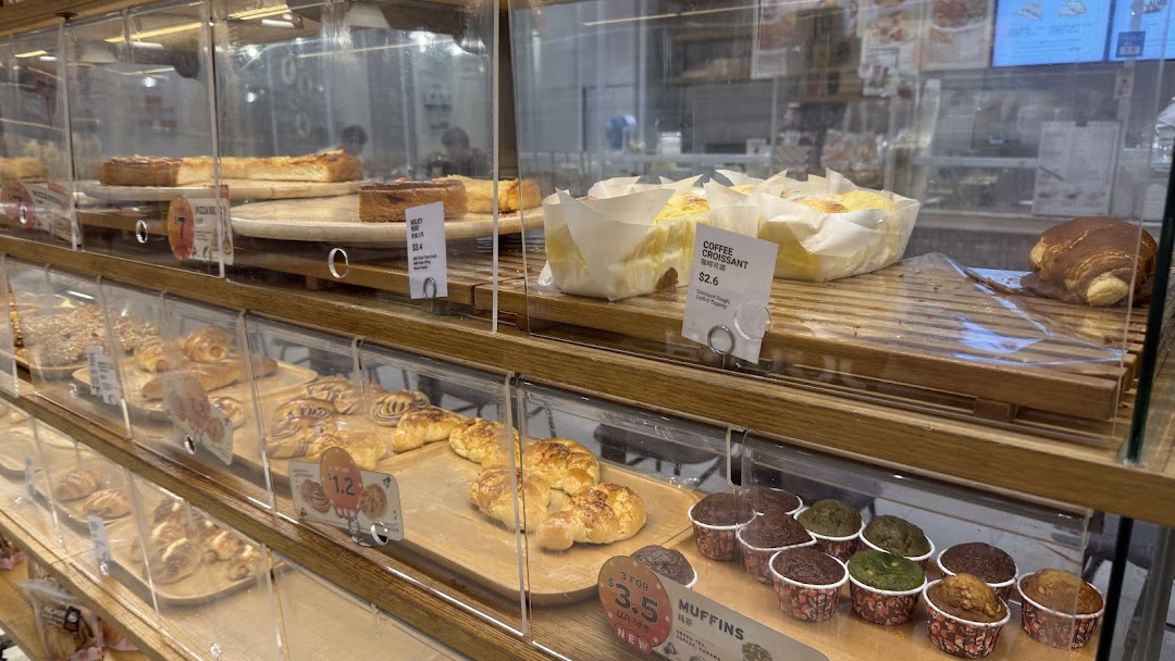 A vibrant display case showcasing a variety of freshly baked pastries, muffins, and cakes at BreadTalk.