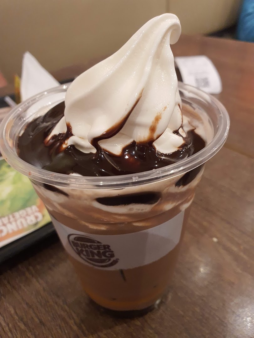 A close-up of a Burger King dessert drink featuring soft-serve ice cream and rich chocolate syrup.