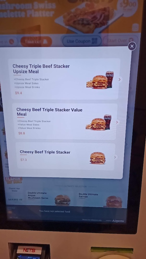 A self-service kiosk screen at Burger King displaying menu options for Cheesy Triple Beef Stacker meals.