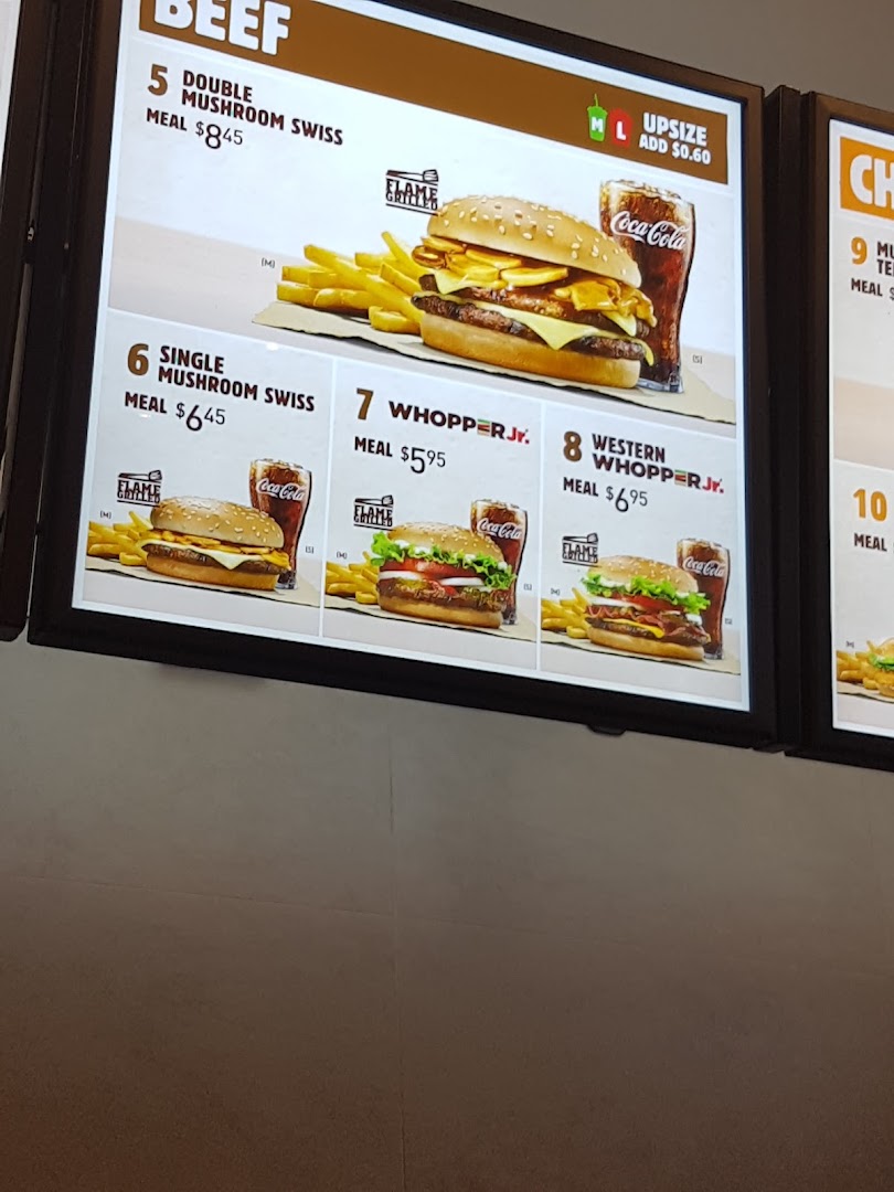 A digital menu board at Burger King showcasing various beef burgers and meal options.