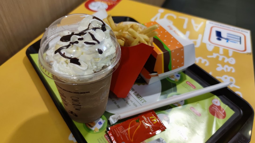 A close-up of a fast-food meal featuring a chocolate frappe, french fries, and a burger on a tray.