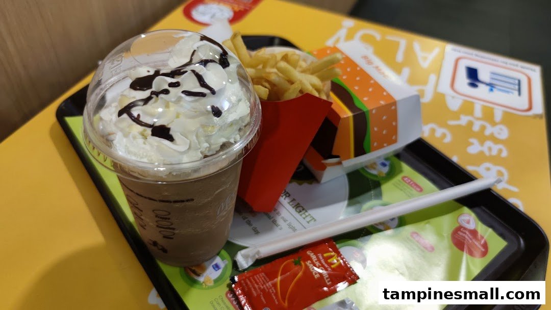 A close-up of a fast-food meal featuring a chocolate frappe, french fries, and a burger on a tray.