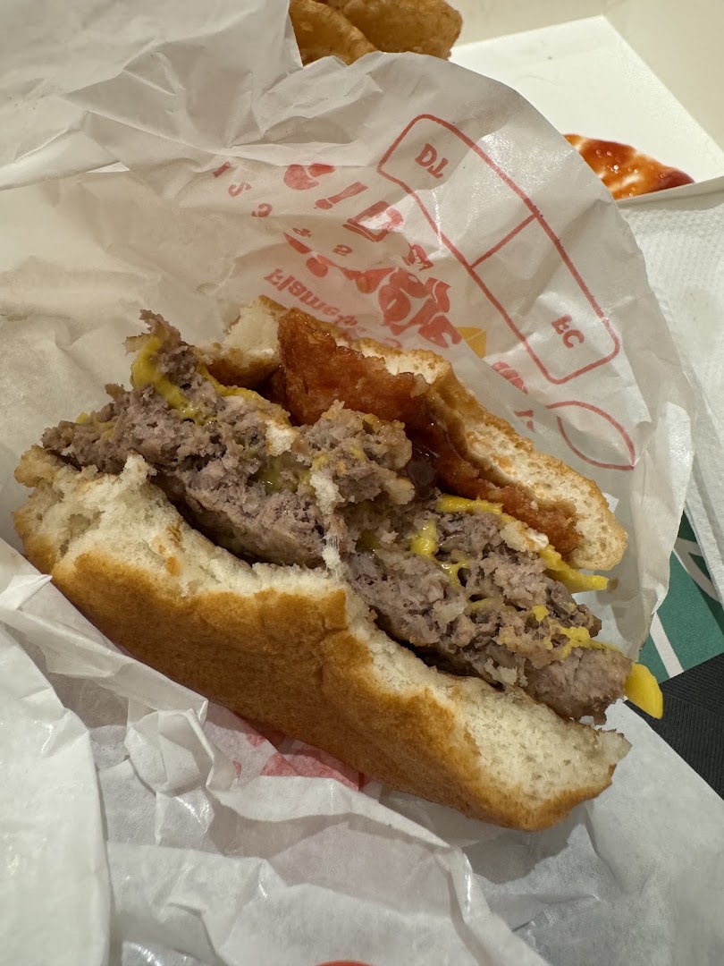 A close-up of a half-eaten Burger King burger with hash browns in a wrapper.