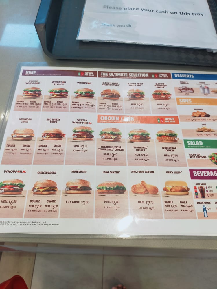 A detailed menu board displaying various burgers, chicken, sides, and beverages with prices.