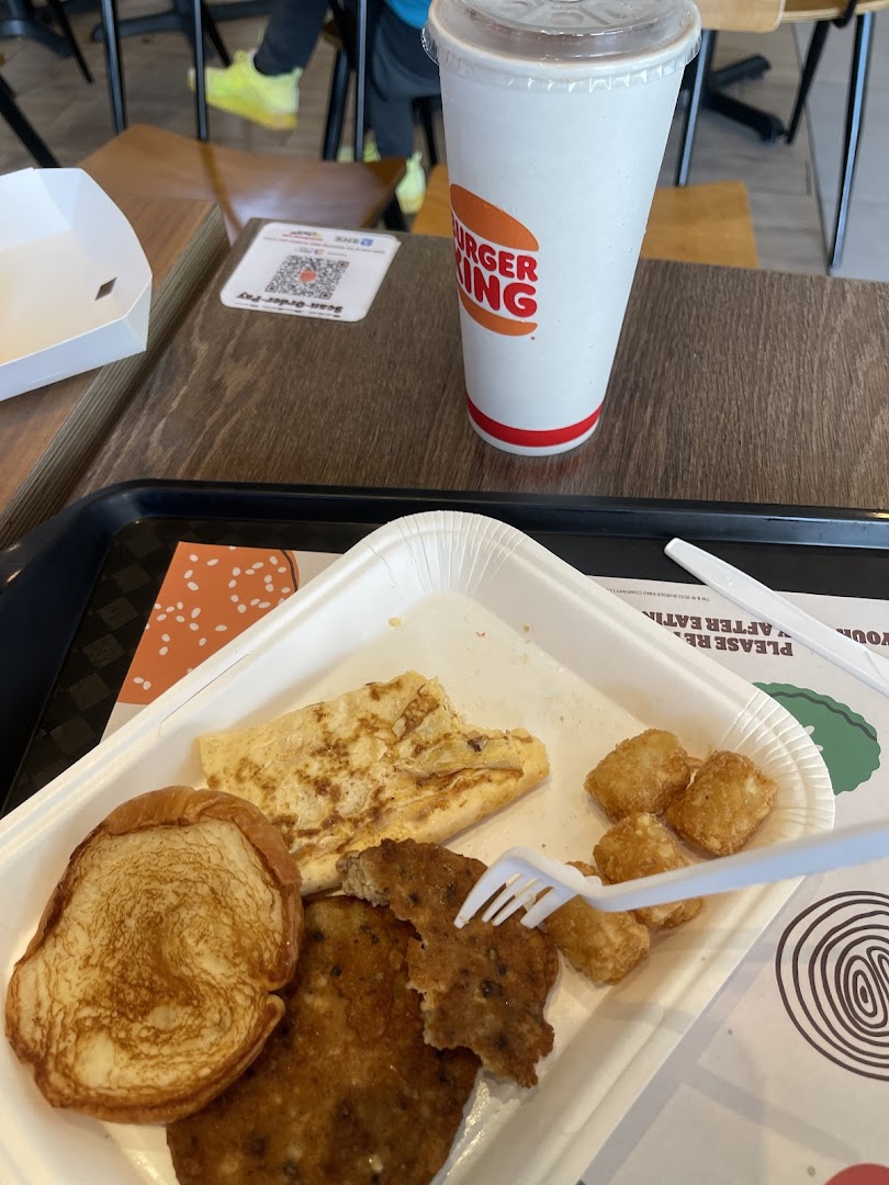 A close-up of a Burger King breakfast meal with a drink on a wooden table.