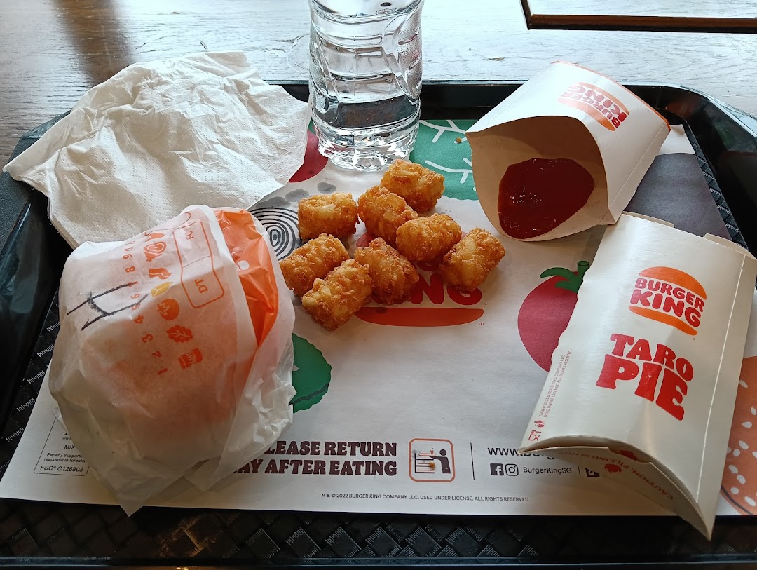 A Burger King meal on a tray, featuring a burger, tater tots, a Taro Pie, and a drink.