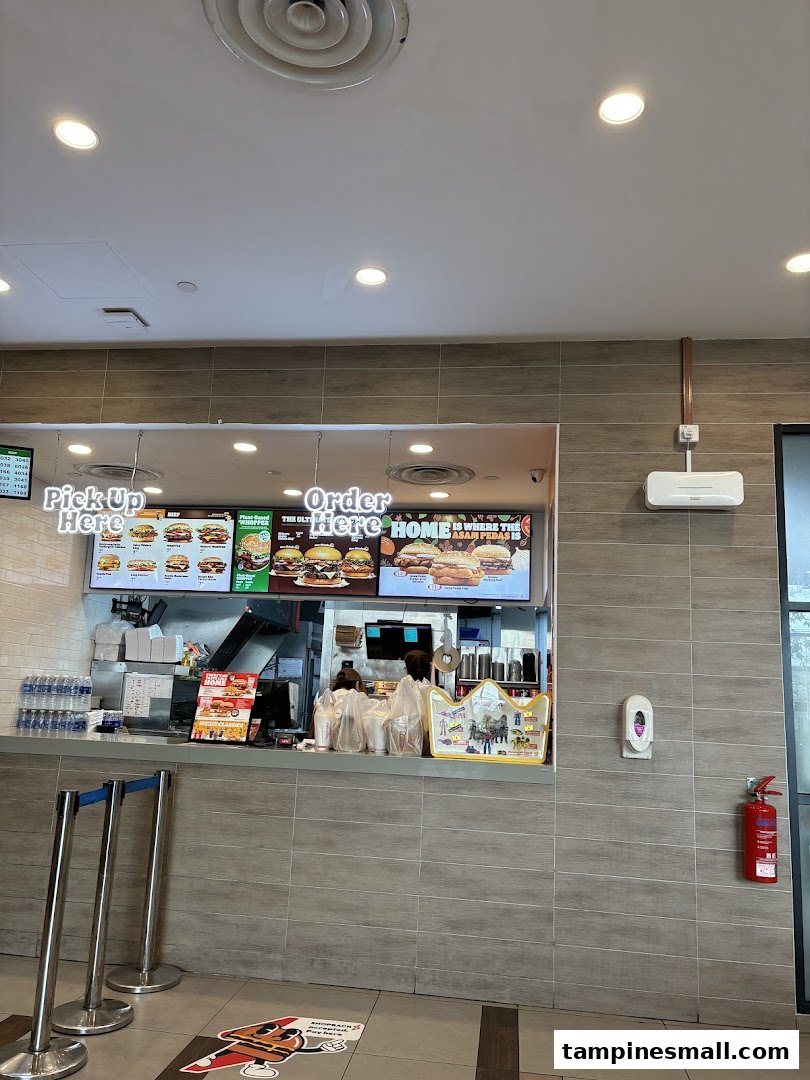 The ordering counter at Burger King Tampines Mall, featuring digital menu boards and queue stanchions.