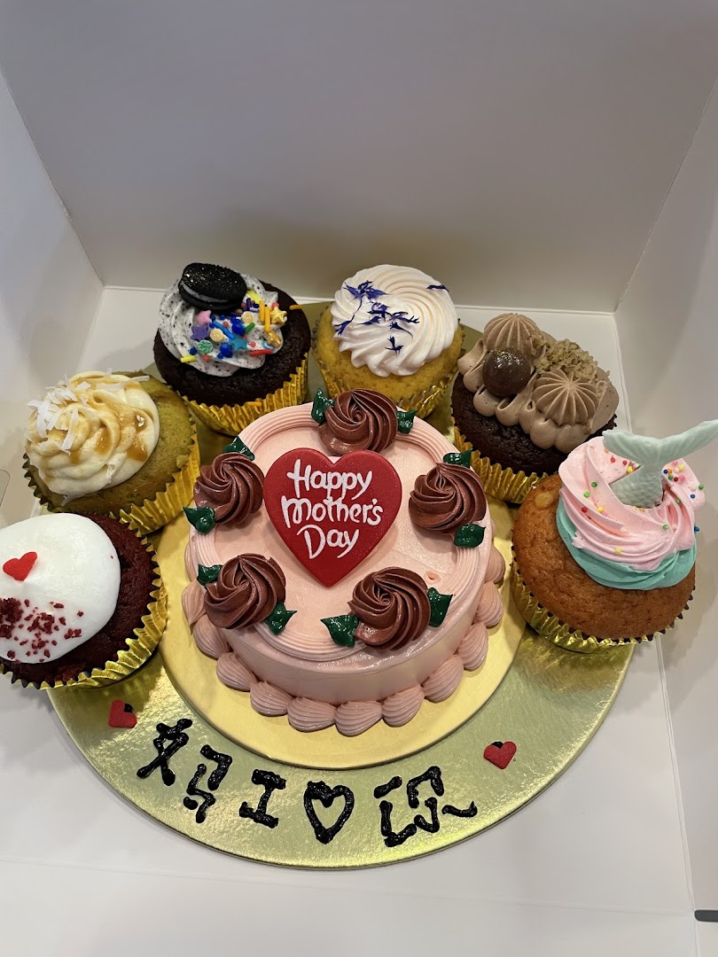A delightful assortment of cupcakes surrounding a 'Happy Mother's Day' cake in a box.