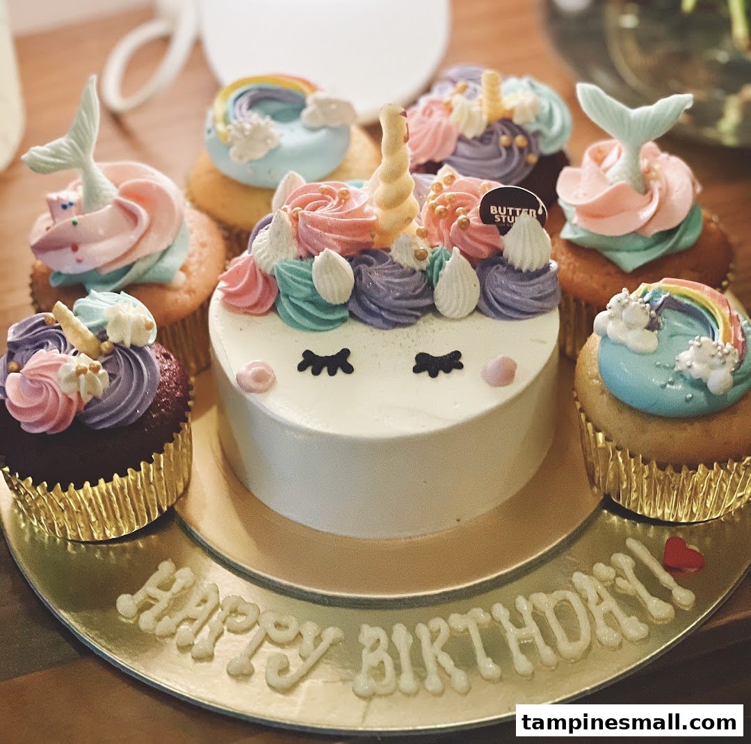 A delightful unicorn cake surrounded by colorful, whimsical cupcakes on a 'Happy Birthday' platter.