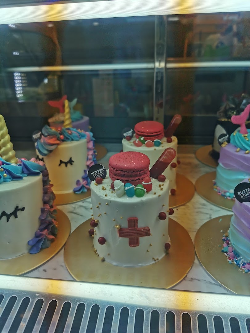 Colorful, custom-designed cakes displayed in a glass case at Butter Studio.