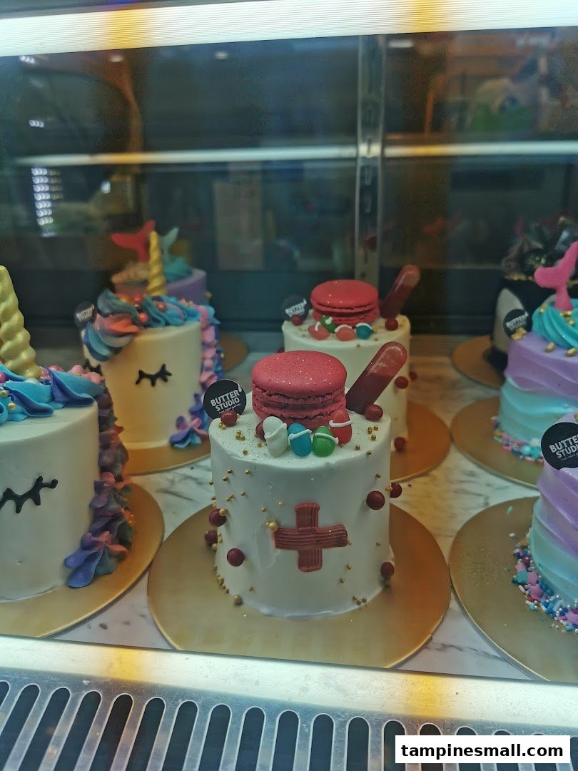 Colorful, custom-designed cakes displayed in a glass case at Butter Studio.
