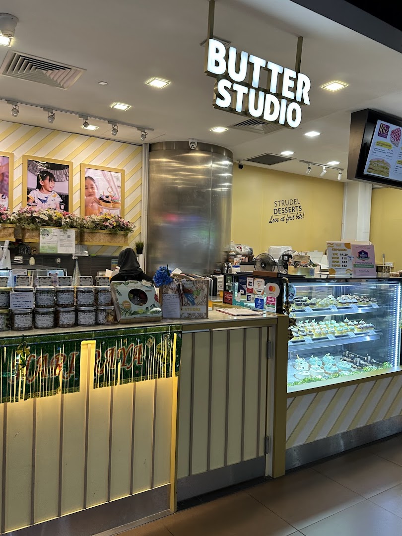 The shop front of Butter Studio, showcasing its dessert display, counter, and bright signage.
