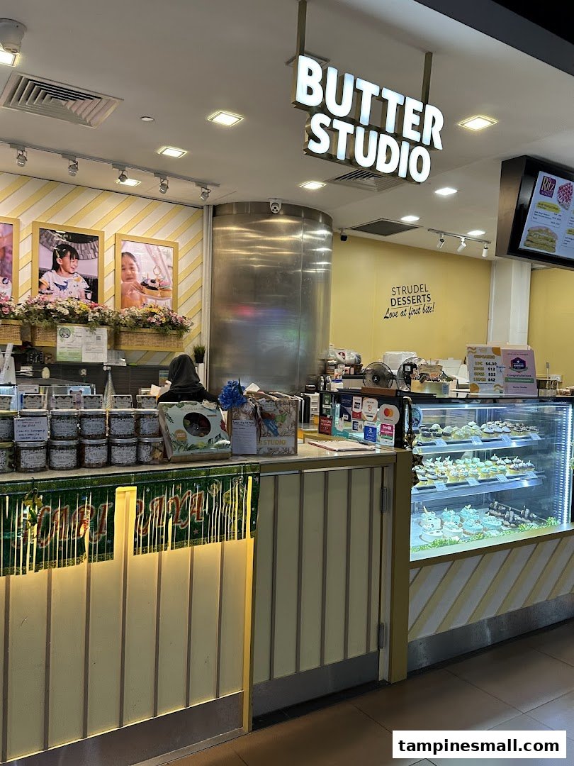 The shop front of Butter Studio, showcasing its dessert display, counter, and bright signage.