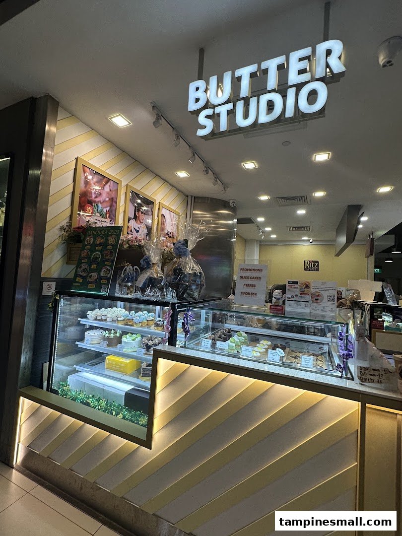 The brightly lit shop front of Butter Studio showcases a tempting array of cakes and pastries in display cases.