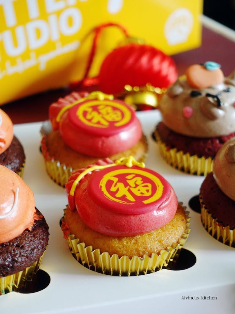 Close-up of festive cupcakes with red and gold decorations, some featuring Chinese characters, from Butter Studio.