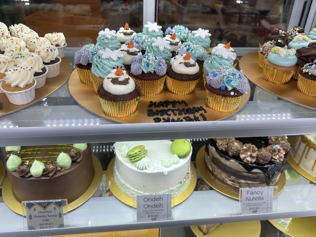 A display case filled with beautifully decorated cupcakes and cakes at Butter Studio.