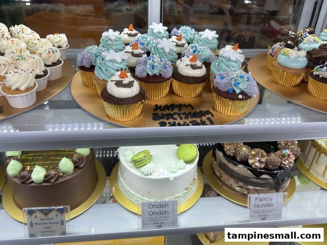 A display case filled with beautifully decorated cupcakes and cakes at Butter Studio.