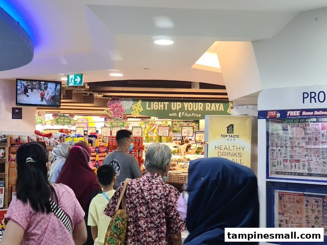 Shoppers browse aisles inside a FairPrice supermarket, featuring promotional displays and products.