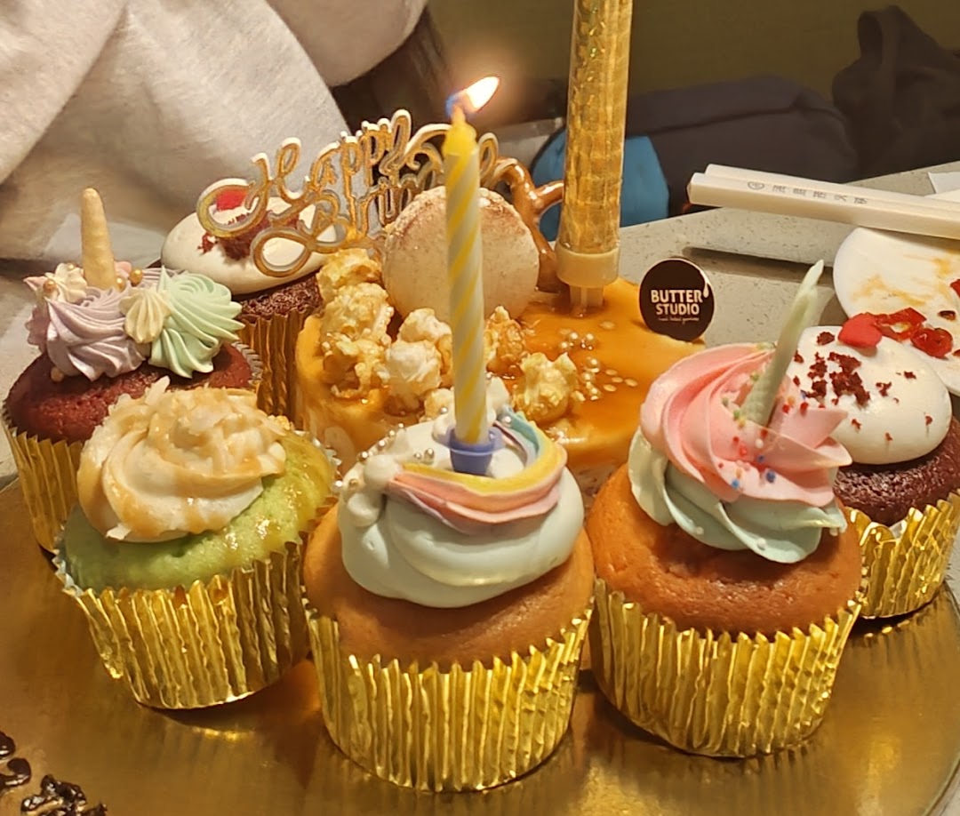 A vibrant assortment of decorated cupcakes with birthday candles and a 'Happy Birthday' topper.