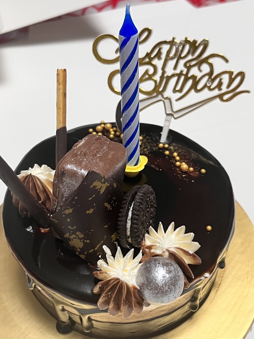 A decadent chocolate birthday cake adorned with various chocolate toppings and a 'Happy Birthday' topper.