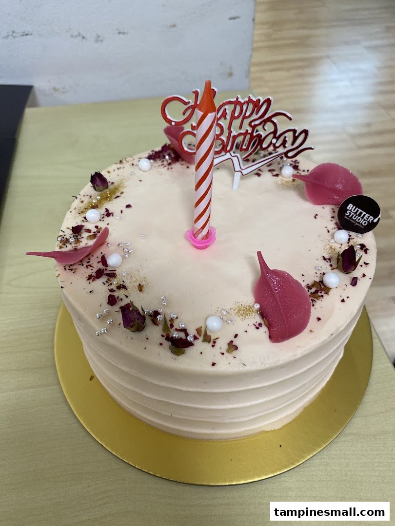 A beautifully decorated birthday cake from Butter Studio with a candle and 'Happy Birthday' topper.
