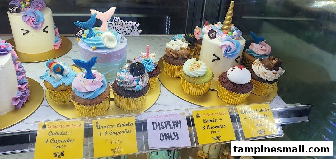 A vibrant display of custom cakes and cupcakes, including unicorn and mermaid themes, with pricing for celebration sets.
