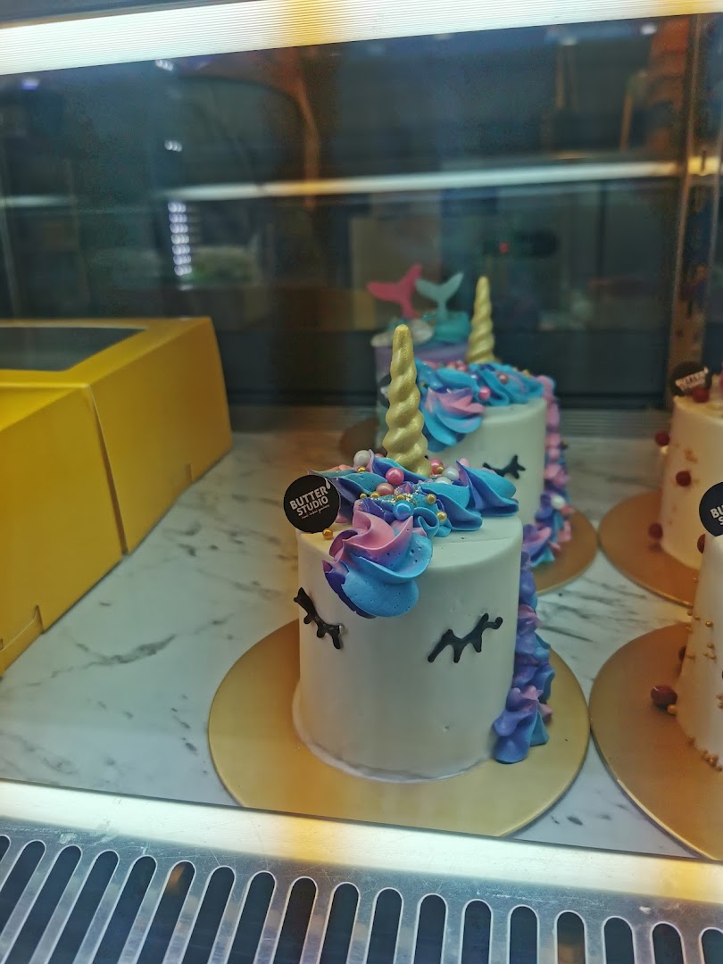 Colorful unicorn and mermaid mini cakes displayed in a glass case at Butter Studio.