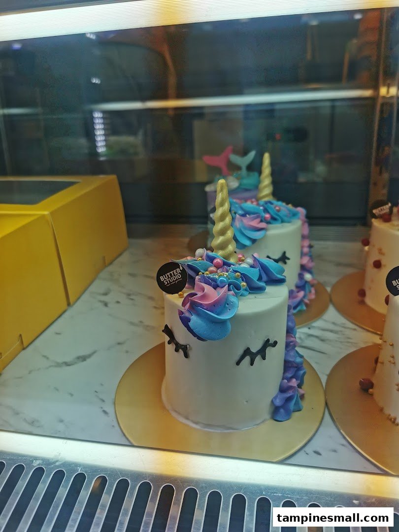 Colorful unicorn and mermaid mini cakes displayed in a glass case at Butter Studio.