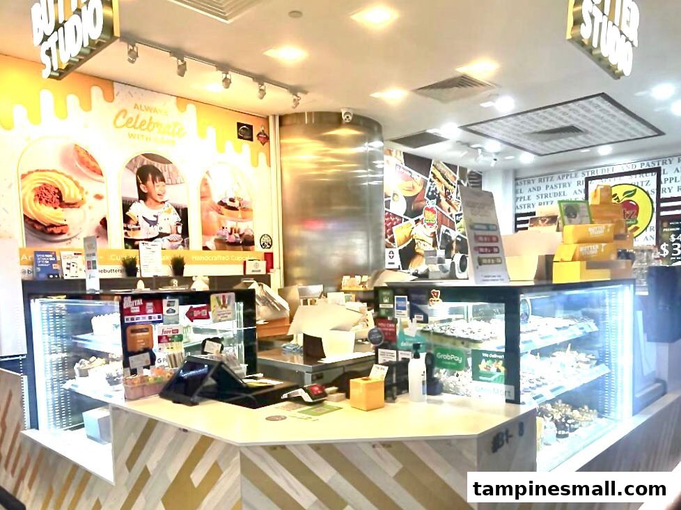 An inviting interior view of Butter Studio, showcasing dessert display cases, a service counter, and vibrant wall decor.