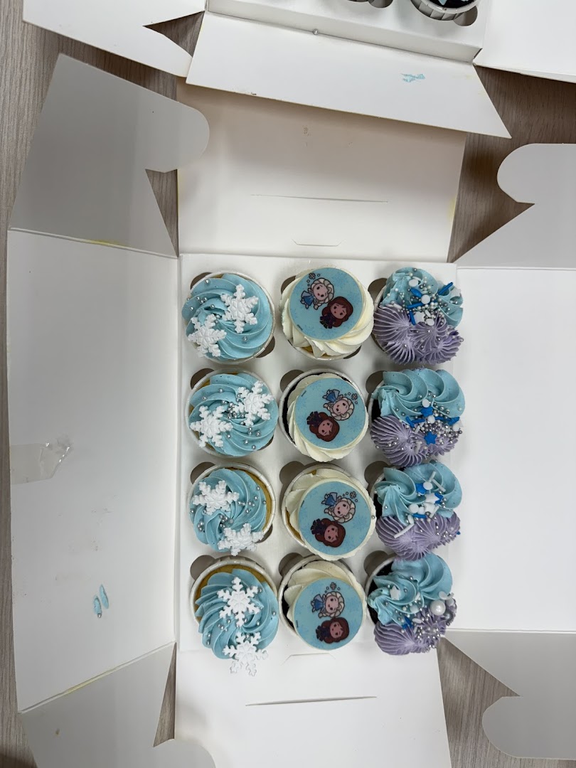 A dozen themed cupcakes in a white box, featuring blue, purple, and character designs.