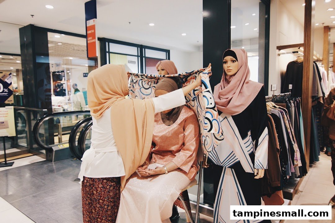 A person adjusts a patterned scarf on a mannequin in a modest fashion boutique, surrounded by stylish clothing displays.